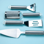 front-view-stainless-kitchen-tools-lying-side-by-side-soft-blue-wave-background-with-free-space